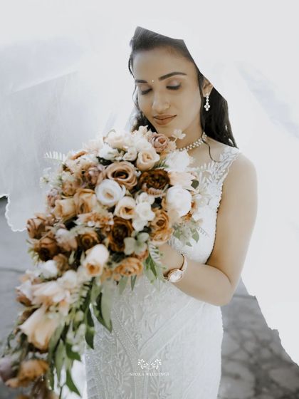 An artistic shot of the bride with her bouquet, her face partially obscured by her flowing veil, creating a dreamy and romantic mood.