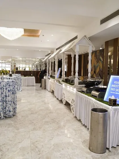 An expansive view of an indoor banquet hall setup. The combination of cocktail tables and a long, elegant buffet line under a grand chandelier shows how I adapt my styling to any venue.