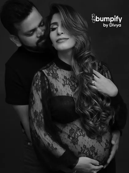 A sensual and intimate black and white portrait. The mom-to-be wears a delicate lace top, and the focus is on the emotional connection between the couple.
