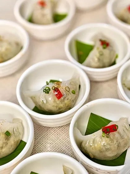A collection of our crystal vegetable dim sum, served in individual white bowls. The fresh chili and spring onion garnish adds a pop of color and flavor.