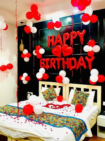 A full view of the birthday bedroom setup. The combination of floating balloons, wall decor, and petals on the bed creates a complete celebratory atmosphere.