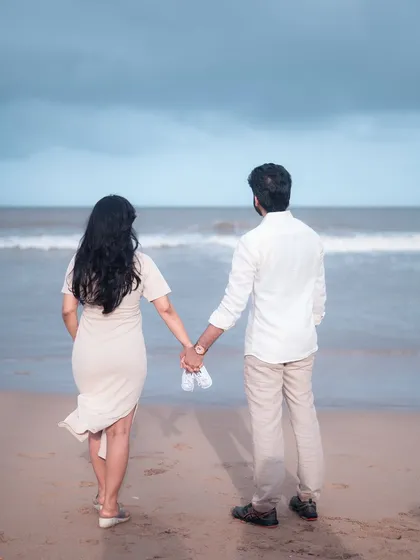Holding hands and looking out at the ocean, this couple is on the brink of a new adventure. The baby shoes they hold are a sweet touch, a promise of the little one who will soon join them.