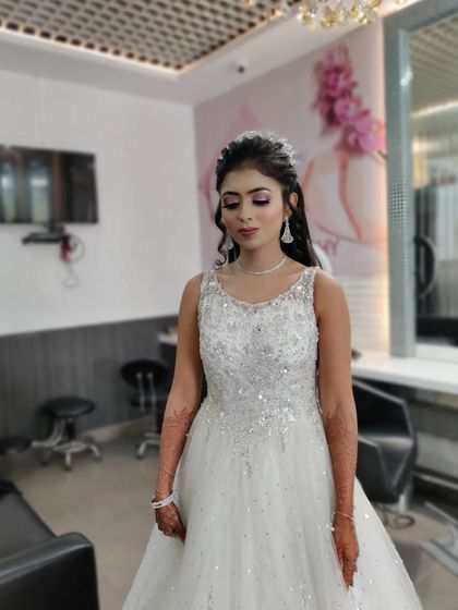 The soft waves and sparkly gown are complemented by a makeup look that focuses on radiant skin and defined eyes, ensuring she shines throughout her special evening.