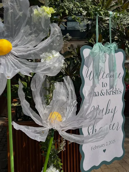 A closer look at the welcome signage, where the elegant script and oversized organza daisies create a charming first impression.