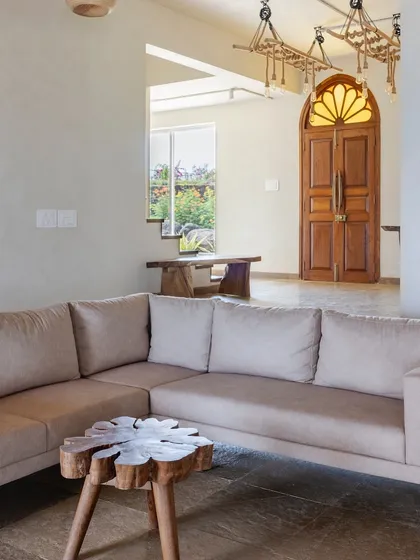 A view from the living room towards the main entrance, featuring a beautifully crafted wooden door with a sunburst glass detail.