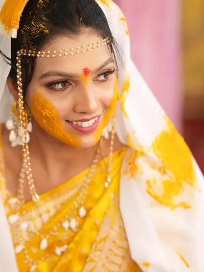Another beautiful shot capturing the bride's radiant smile and the traditional elements of her Haldi look.
