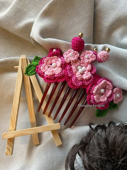 Our pink floral bun comb is displayed on a mini easel, highlighting it as a small piece of wearable art. The different shades of pink create a beautiful gradient effect.