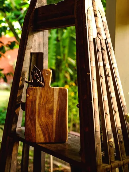 A rustic wooden chopping board from Araana Home, styled in a natural, outdoor setting. The image evokes a sense of connection to nature and handcrafted quality.