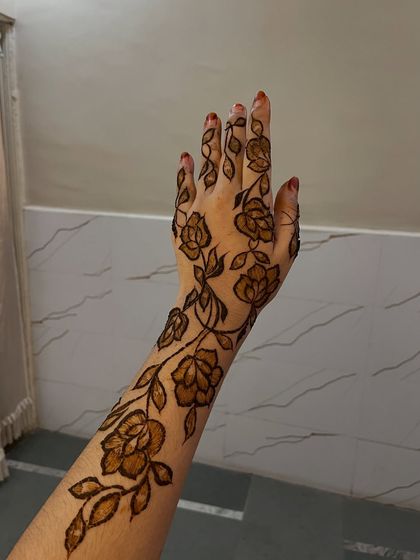 A single arm view of a rose vine design, a classic and popular Gulf henna style.