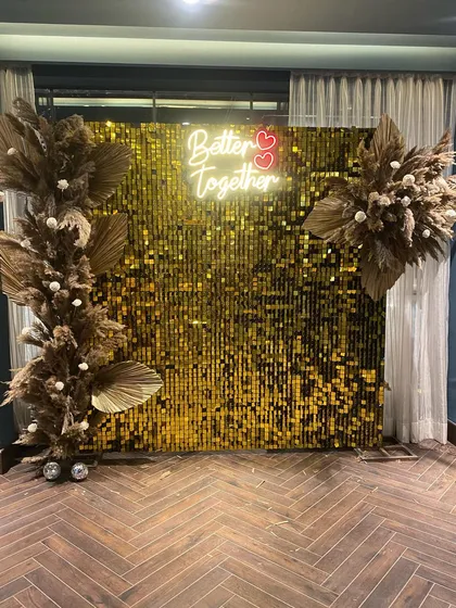 Our gold sequin shimmer wall makes a glamorous statement for any pre-wedding event. Paired with a custom "Better Together" neon sign and dried floral arrangements, it serves as a perfect photo backdrop for an engagement party or anniversary.