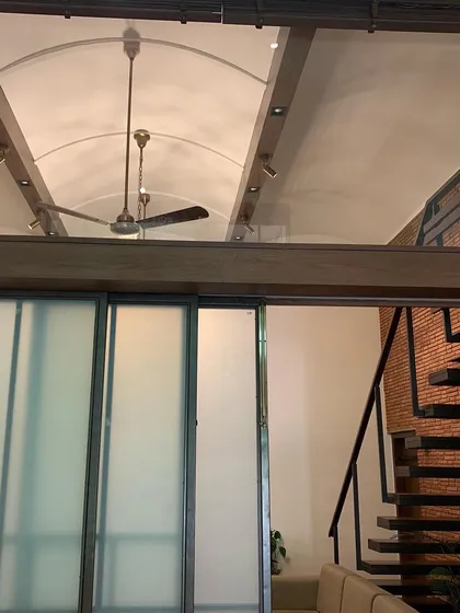 A vaulted ceiling made of translucent glass panels diffuses light beautifully into this interior space. This innovative roofing solution, combined with exposed beams, adds a soft, ethereal quality to the room.