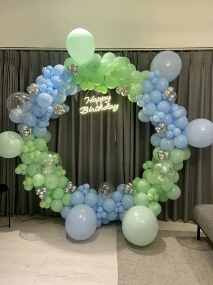 A cool-toned balloon ring in shades of green and blue with a neon sign.
