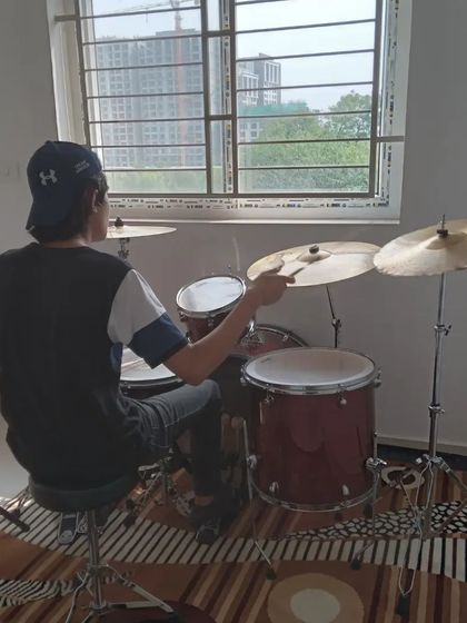 A student practicing on the drums, with a nice view of the city outside. A great space to get inspired.