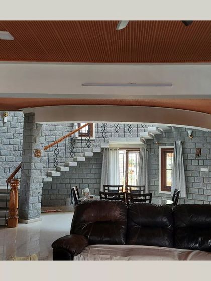 An open-plan living and dining area, where stone walls and a floating staircase create a sense of spaciousness and fluidity.