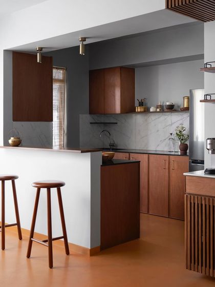 A wide view of the kitchen, showing the custom wood cabinetry, breakfast counter, and bar area. I design kitchens to be the hardworking heart of the home, with durable materials and smart layouts.