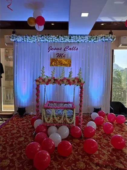 For this naming ceremony, we decorated the baby's cradle (palna) with delicate pink and white artificial flowers. The backdrop of white curtains and soft blue uplighting creates a serene and beautiful focal point for the event.