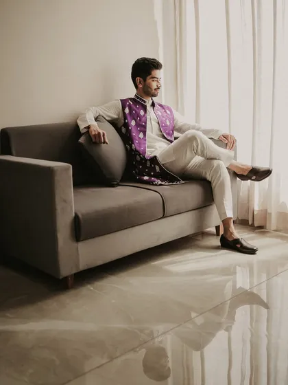 A relaxed and stylish portrait of the groom before the festivities. The natural light from the window and his confident pose create a calm yet dapper image.