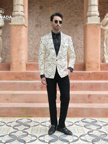 This full-length shot against a classic backdrop highlights the tuxedo's versatility, fitting for both modern and traditional settings.