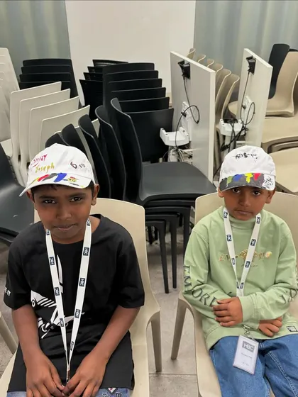 Two young boys sitting patiently after finishing their cap painting. It's wonderful to see them so proud of their work.