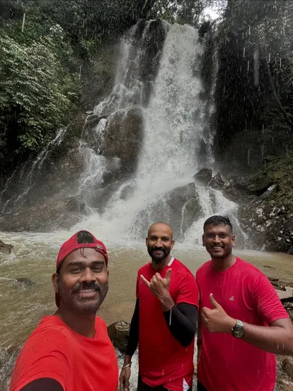 Three friends taking a selfie after a refreshing dip, with a beautiful waterfall as the perfect backdrop.