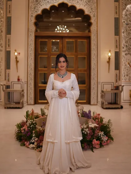 A full-length shot of the white lehenga in a grand lobby. The outfit is simple, elegant, and timeless.
