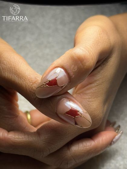 An abstract design featuring a shattered glass effect, with red fragments outlined in fine gold lines on a nude base.