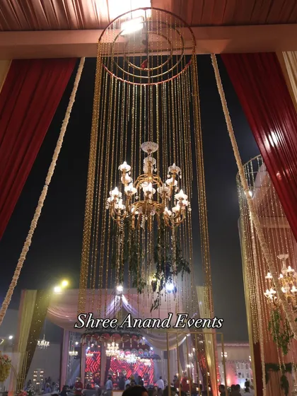 A close-up of a beautiful chandelier surrounded by a rain of golden beads, a signature element that adds texture and luxury.