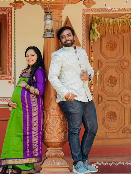 A relaxed and happy couple posing against a traditional house backdrop.