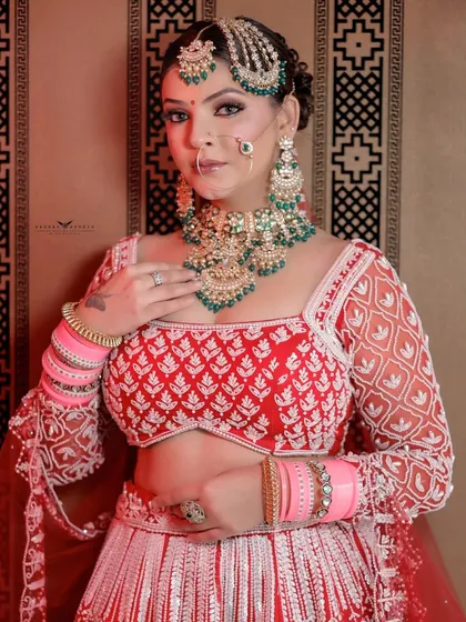 A mid-shot of the bride, highlighting the contrast between the red blouse and the white detailing on the lehenga.