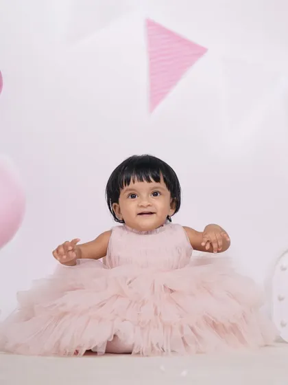 A delightful portrait of a baby girl in a fluffy pink dress, surrounded by birthday decorations in the studio. I focus on capturing these precious, fleeting expressions of wonder.