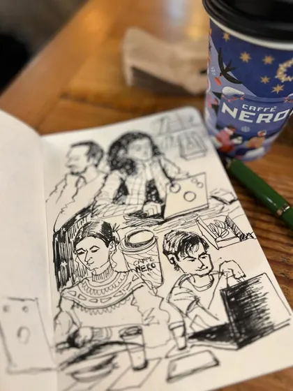 My sketchbook and a cup of coffee, the perfect combination. A close-up of my ink drawings of people at the cafe.