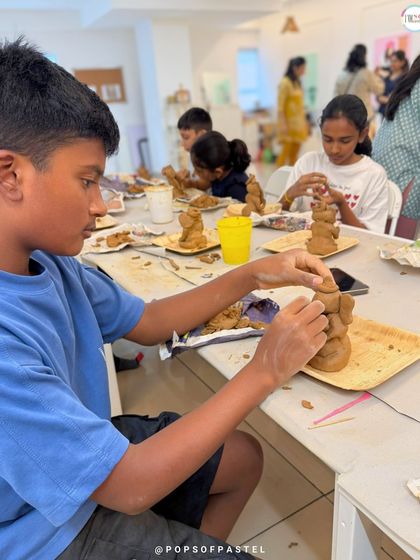 A young artist concentrates on adding details to his Ganesha, learning patience and precision in this hands-on sculpting workshop.