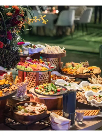 A wide shot of a beautiful outdoor grazing table, laden with Mediterranean and Middle Eastern dips, salads, and breads. This setup is perfect for a relaxed yet sophisticated garden party or sundowner.