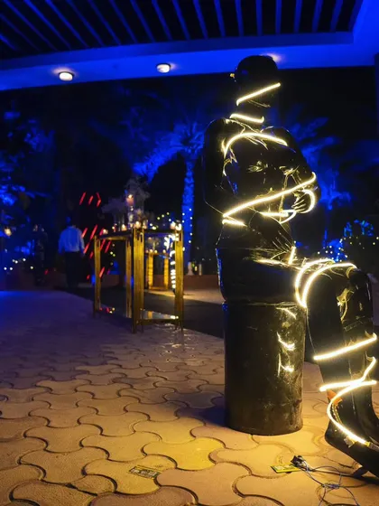 A unique decor element: a statue wrapped in glowing neon wire, adding an artistic and edgy vibe to the party's entrance pathway.