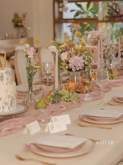 A beautifully set table for an anniversary brunch. The soft lighting, delicate floral arrangements, and carefully chosen tableware come together to create a scene of understated elegance and romance.