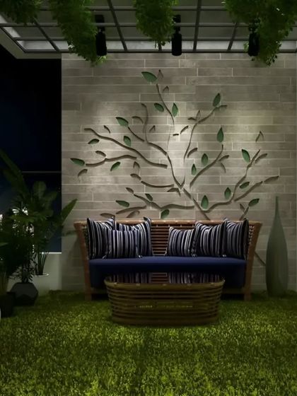 A cozy balcony designed for nighttime relaxation. The space features artificial turf, a comfortable sofa, and a beautiful tree-like art piece on the wall, all softly lit for a serene ambiance.