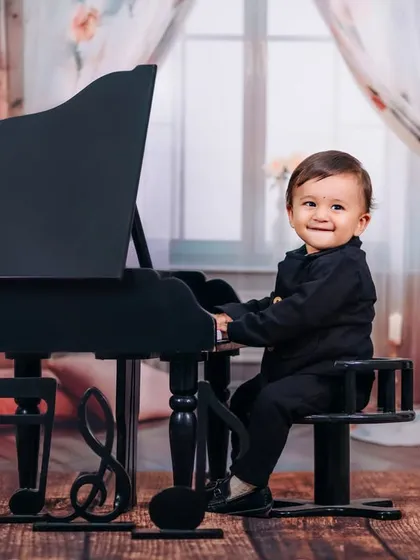 A classic portrait of a little gentleman at his miniature grand piano. Our studio setups, like this musical theme, are designed to capture your child's budding personality and charm.