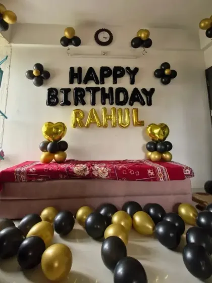 A simple home decoration with black and gold balloons and foil letters for "RAHUL".