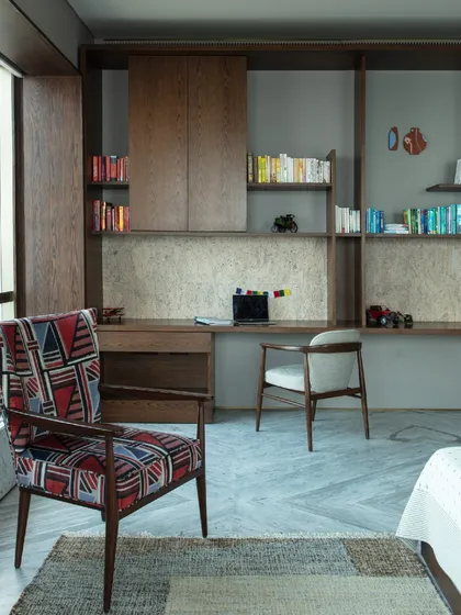 The daughter's bedroom in our Kolkata project, featuring a custom study area and a vibrant armchair. The design balances youthful energy with sophisticated elements.
