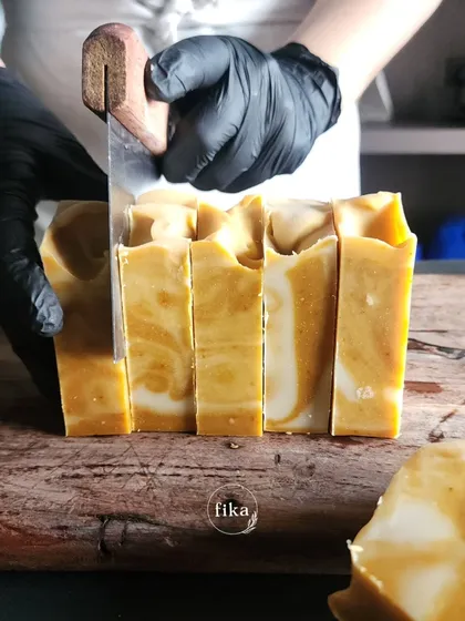 A close-up of me hand-cutting a marbled turmeric soap bar. The creamy white and golden yellow swirls are created during the pouring process, ensuring no two bars are exactly alike. This is the beauty of artisan craftsmanship.