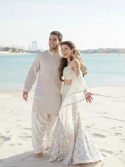 A sunny beach portrait of Alya and Shivaan. Their happy, relaxed smiles and the beautiful seaside location create a perfect destination wedding portrait.
