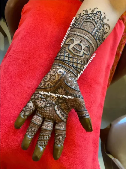 A detailed bridal arm design featuring architectural elements inspired by royal palaces. The use of fine lines and filled spaces creates a rich texture that extends from the wrist to the fingers.