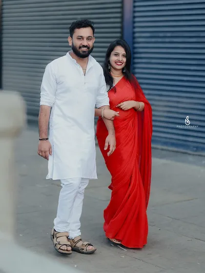 A simple, elegant portrait of the couple. The bold red of her saree stands out beautifully against the blue wall.