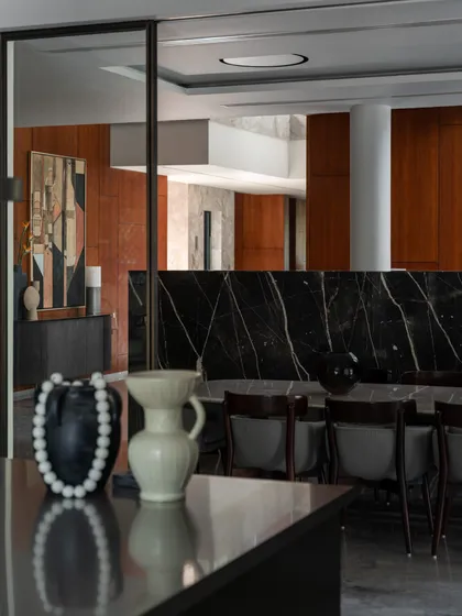 A close-up of the dining area, showing how decorative objects and the texture of the marble partition contribute to a layered and sophisticated interior.