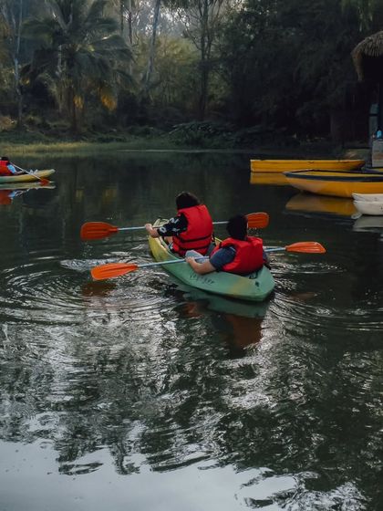 A couple enjoys a quiet moment kayaking on the lake, surrounded by the reflection of the trees on the water.
