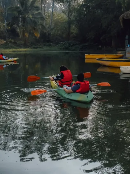 A couple enjoys a quiet moment kayaking on the lake, surrounded by the reflection of the trees on the water.