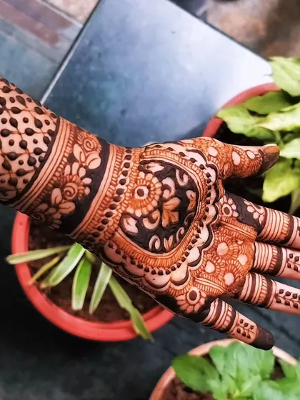 A close-up view of the heart-motif mehendi. You can see the delicate floral and leaf patterns that fill the rest of the hand, creating a rich and dense design.