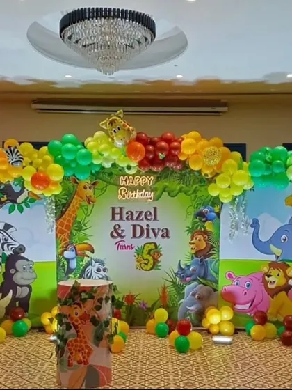 A classic jungle safari theme, perfect for a kid's birthday. This setup includes a vibrant animal-print backdrop, a multi-colored balloon arch, and character cutouts of lions, zebras, and giraffes.
