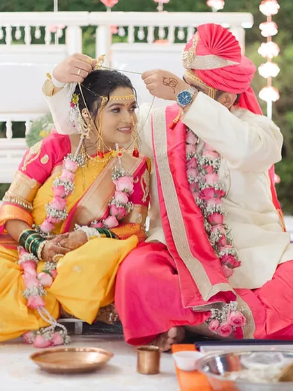 A beautiful ritual moment, with the groom tying the mangalsutra. The bride's expression is one of serene happiness.