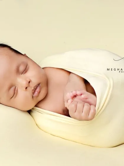 A simple, beautiful portrait of the baby in a yellow wrap against a matching background.